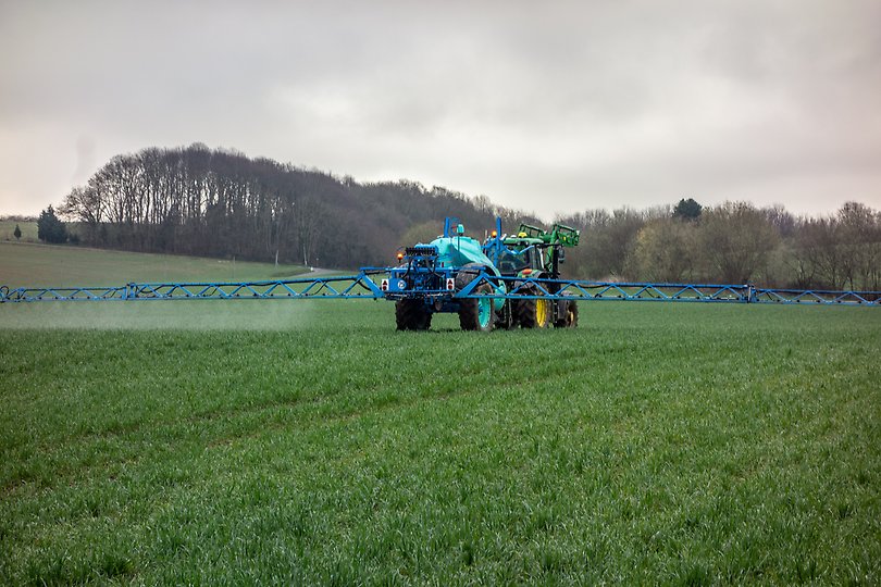 Traktor, som sprider bekämpningsmedel på gröda.